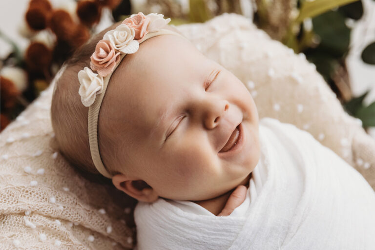Millie Jo smiling sweetly in a blush wrap with floral headband at Reflection Images by Tracy Rowell in Florence SC