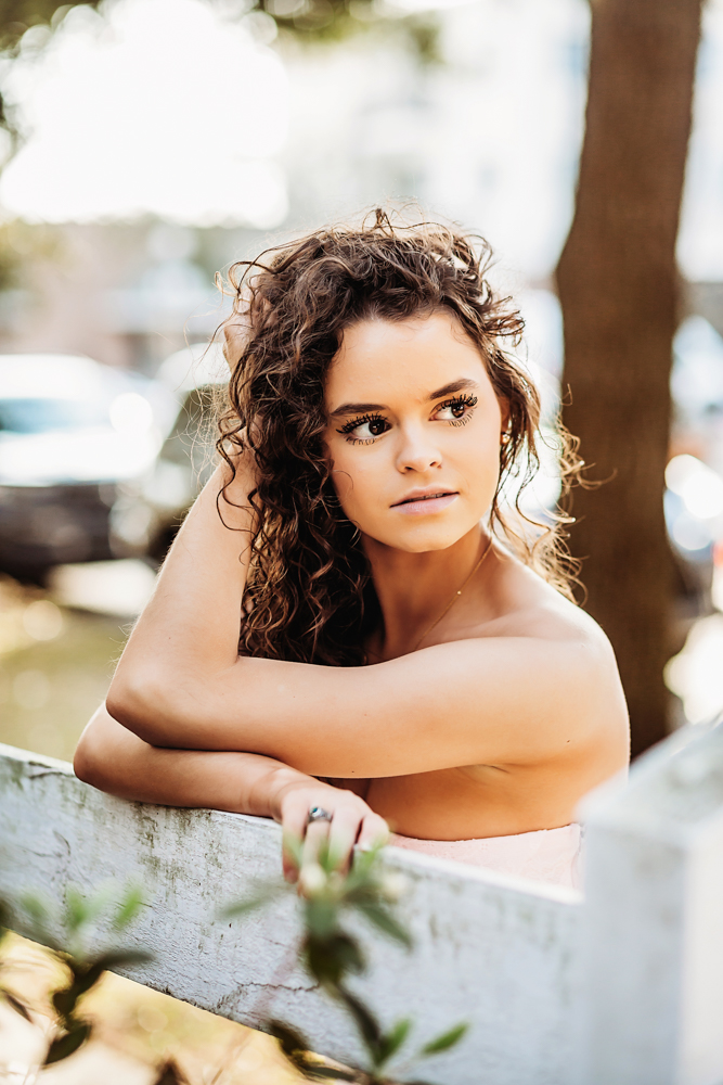 hayden leaning forward on railing Georgetown SC golden hour curls