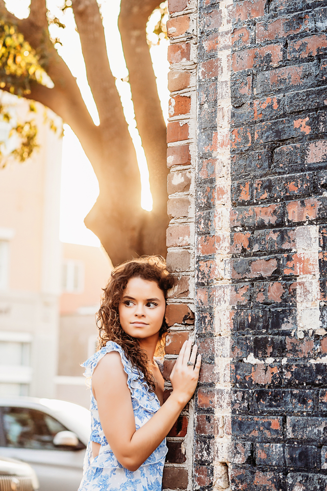 hayden posing by vintage painted brick wall in golden sunlight Georgetown SC reflection images