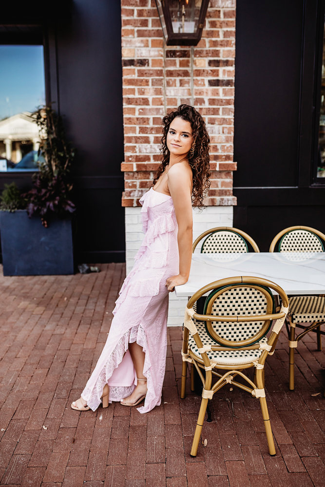 hayden in pink dress leaning back against a table