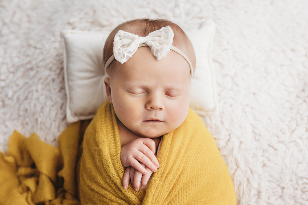 Close-up of Millie Jo in mustard wrap with ivory bow on white flokati at Reflection Images by Tracy Rowell in Florence SC