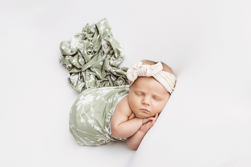 Millie Jo in sage floral wrap with cream bow, sleeping on her side at Reflection Images by Tracy Rowell in Florence SC