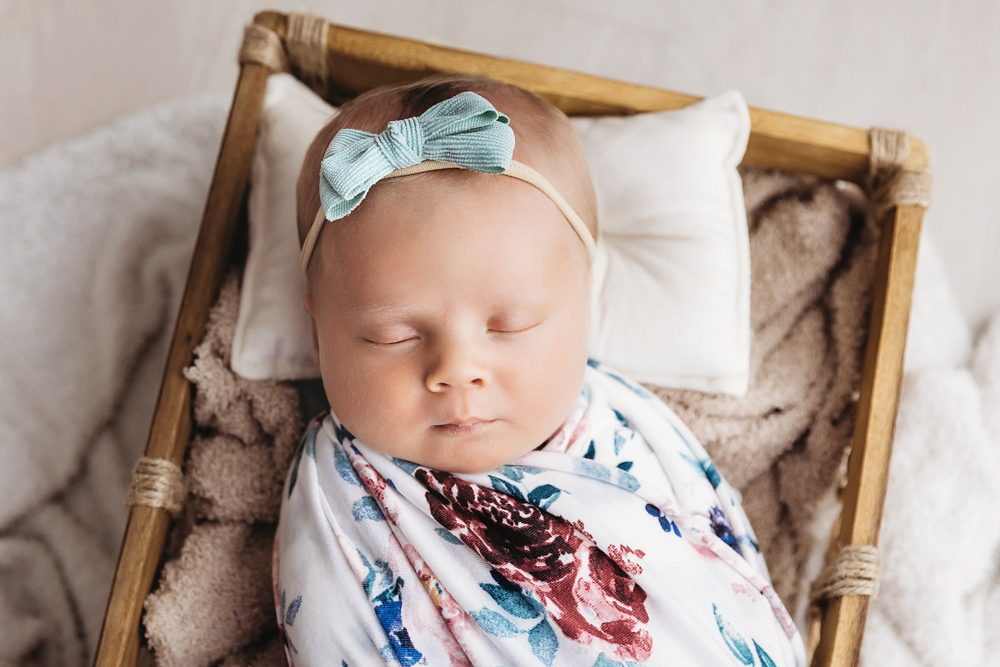 Close crop of Millie Jo wrapped in floral swaddle, tucked in basket at Reflection Images by Tracy Rowell in Florence SC