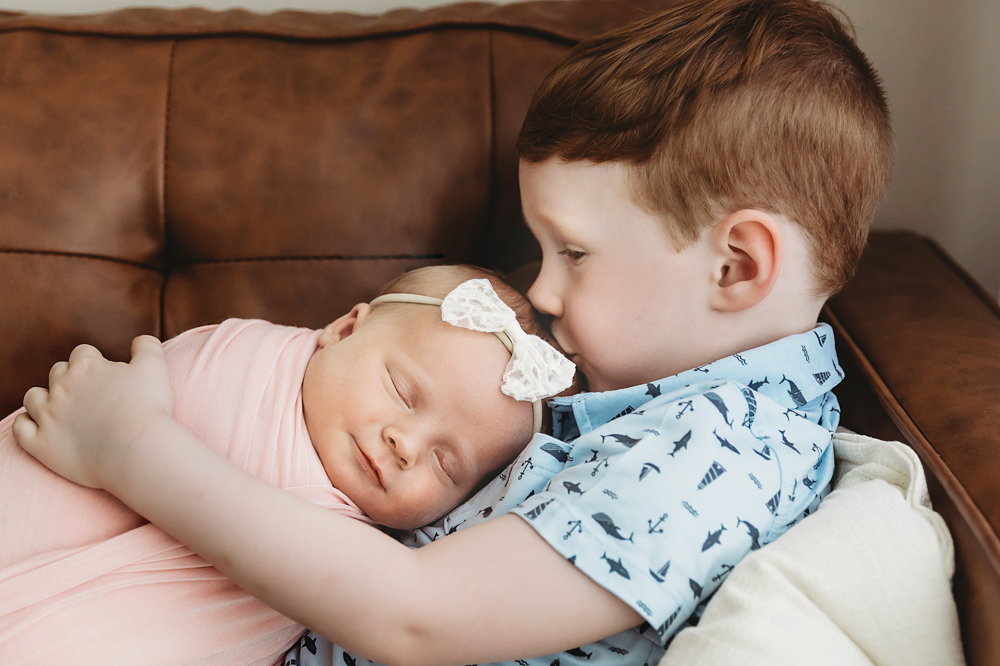 Big brother kissing Millie Jo head as she sleeps wrapped in blush at Reflection Images by Tracy Rowell in Florence SC