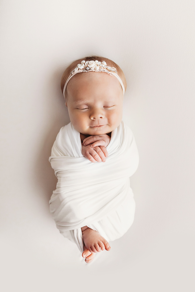 Top-down pose of Millie Jo with hands folded in a soft white wrap at Reflection Images by Tracy Rowell in Florence SC