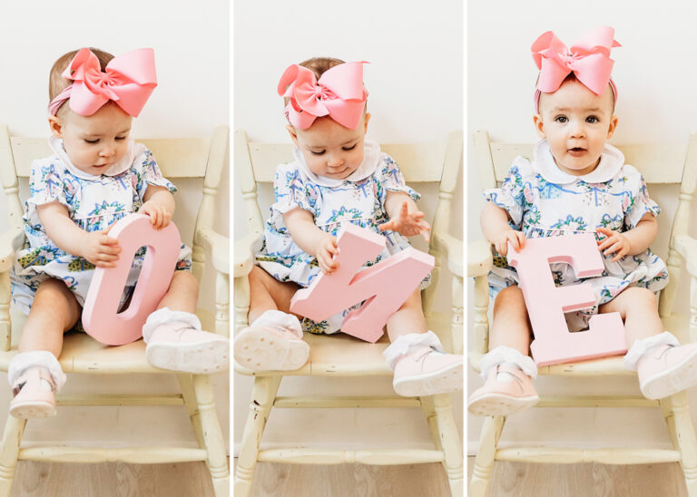 Elsie sitting in a little chair with pink bow, holding pink wooden “O” "N" "E" letters, part of ONE set at Reflection Images by Tracy Rowell in Florence SC