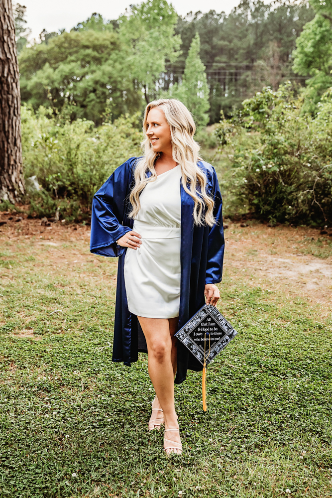 Kristina showing her decorated cap with intricate photo border while standing outdoors with pine trees at Reflection Images by Tracy Rowell in Florence SC