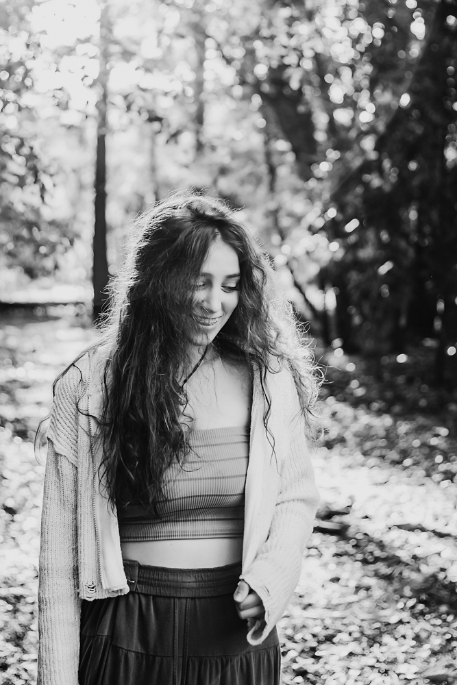 Black and white portrait of Eve with soft smile, turquoise top and sweater, in wooded Florence SC location…