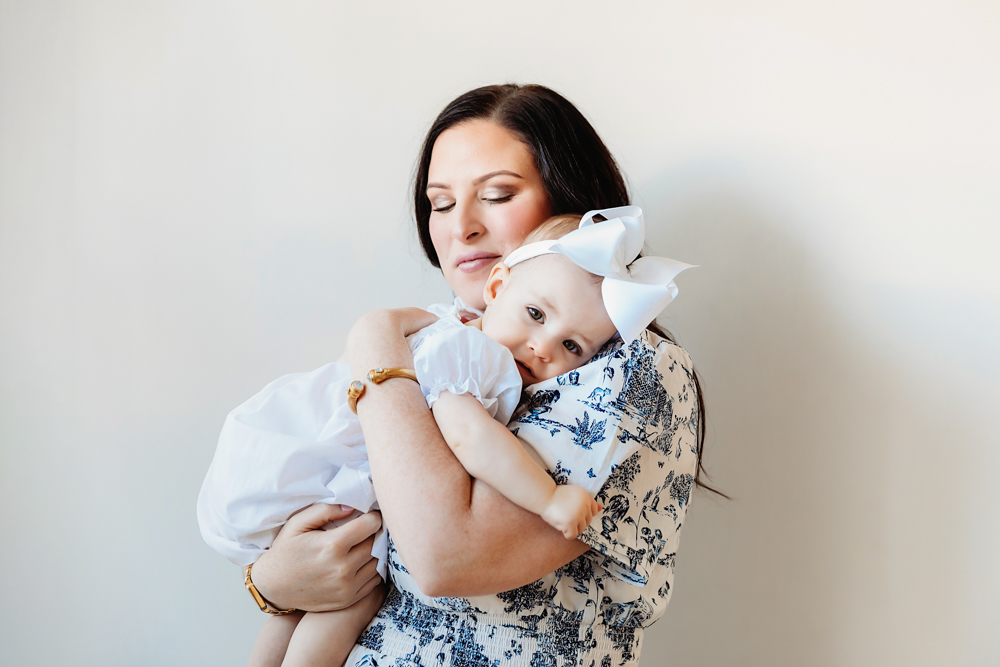 Sweet portrait of mom and Elsie smiling together, white dress with bow, simple studio setting at Reflection Images by Tracy Rowell in Florence SC