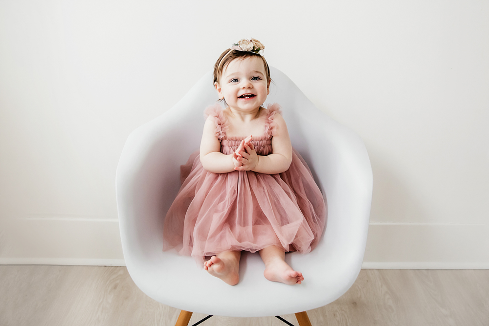 Aubrey sitting in a modern white chair wearing a dusty pink tulle dress and smiling brightly at Reflection Images by Tracy Rowell in Florence SC