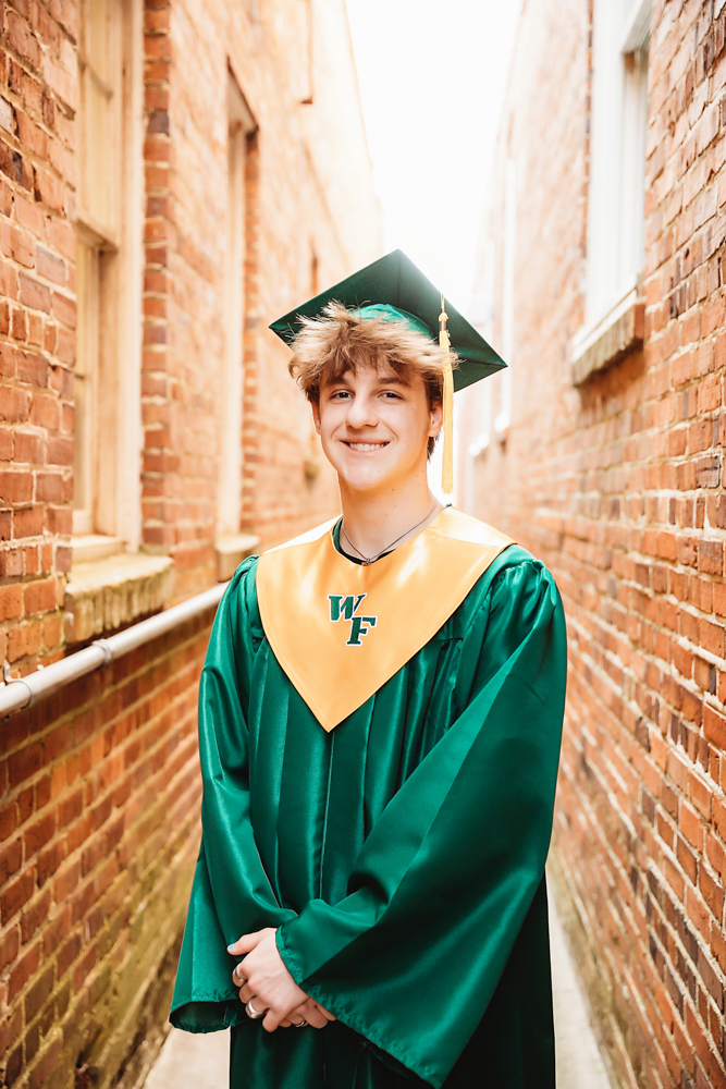 Close-up portrait of Jack in his graduation attire with WF gold stole, smiling proudly in downtown Florence with Reflection Images by Tracy Rowell