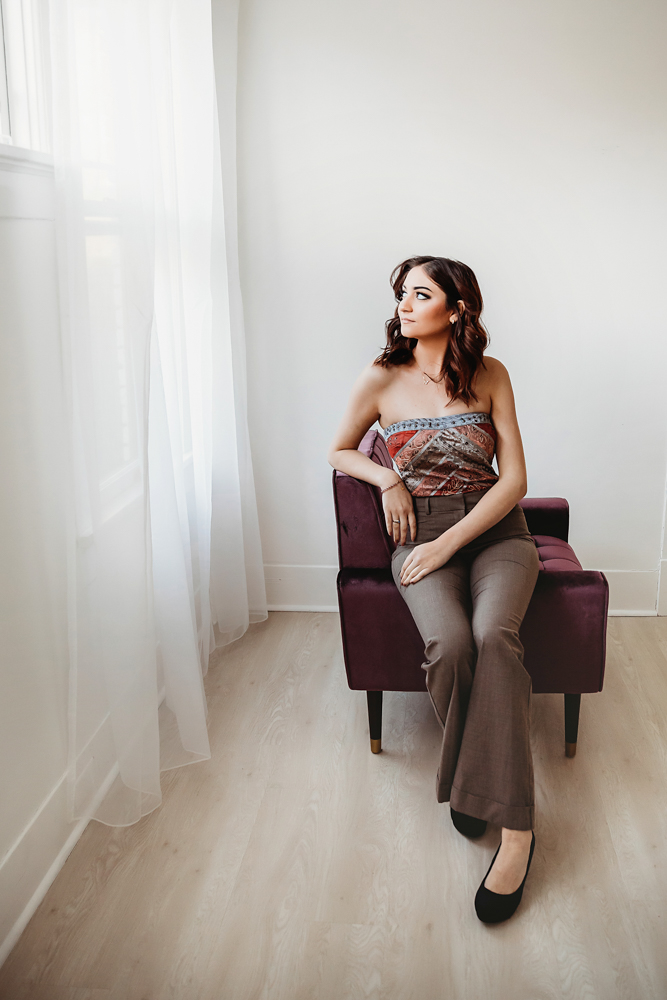 Patricia seated on purple chair by window wearing strapless patterned top and brown pants at Reflection Images by Tracy Rowell in Florence SC