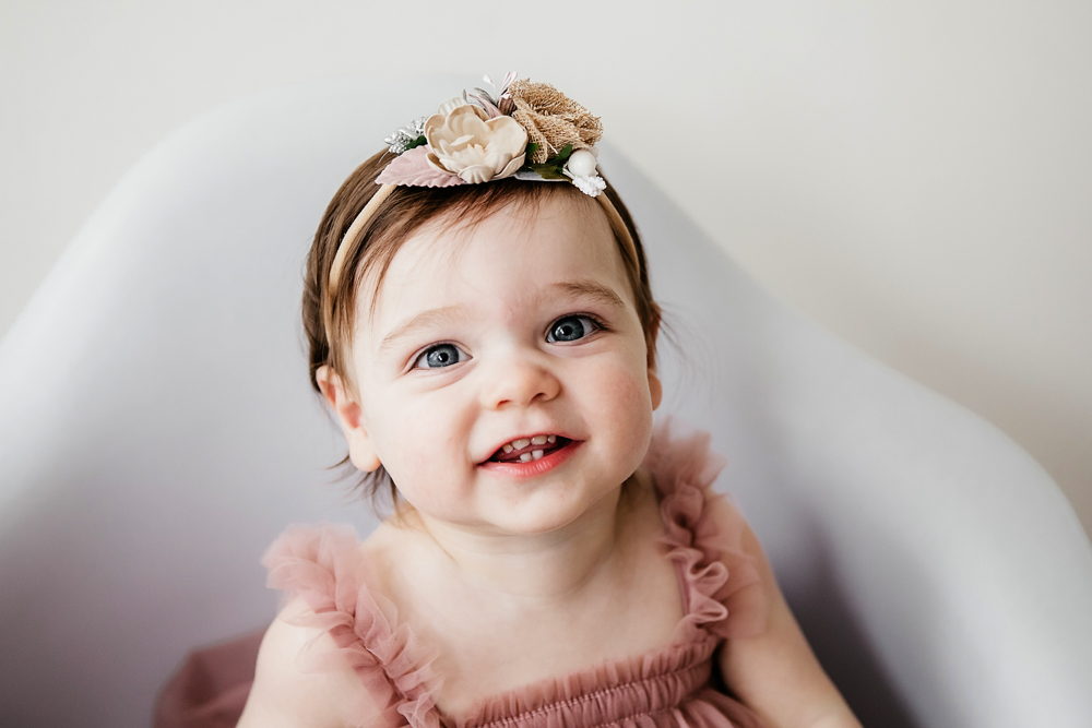 Close-up of Aubrey wearing a flower headband and ruffled pink dress, smiling with soft light at Reflection Images by Tracy Rowell in Florence SC
