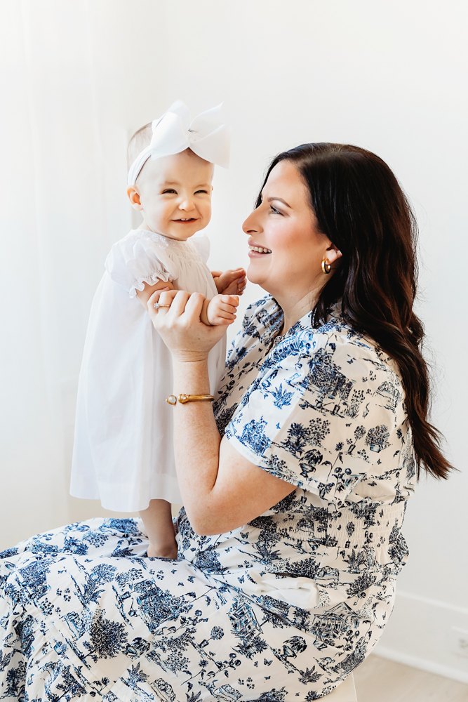 Happy portrait of Elsie with mom, white dress with big bow, mom in blue patterned dress at Reflection Images by Tracy Rowell in Florence SC