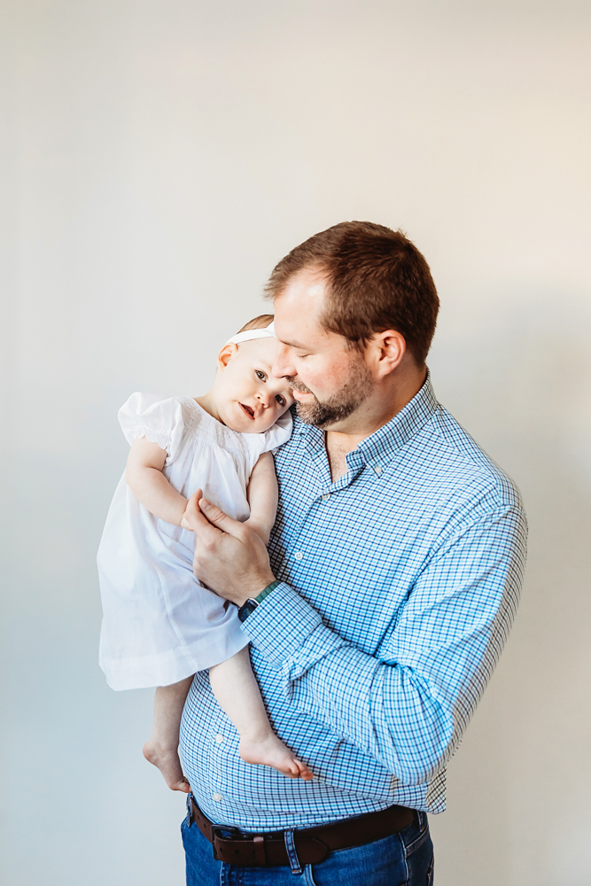 Dad holding Elsie close, her head resting on his chest, soft studio backdrop at Reflection Images by Tracy Rowell in Florence SC