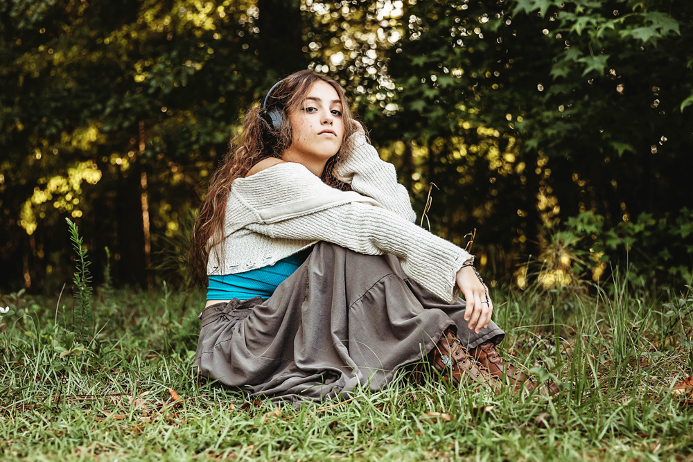 Eve seated in grass with turquoise bandeau and boots, glancing sideways with headphones against trees at Reflection Images by Tracy Rowell in Florence SC