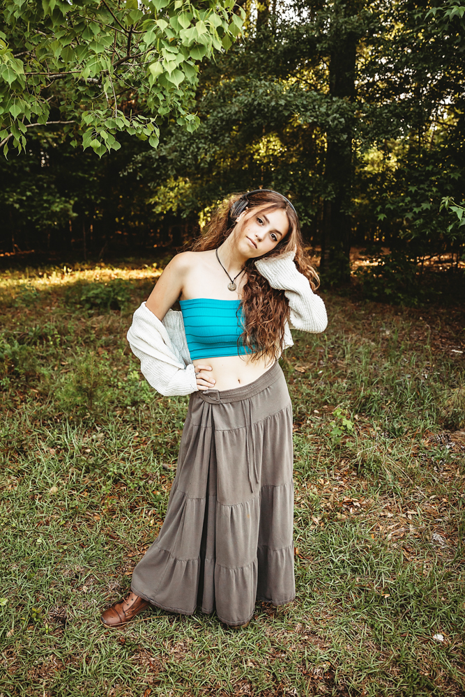 Eve standing in turquoise top and layered skirt, cream sweater falling back, head tilted playfully under leafy tree at Reflection Images by Tracy Rowell in Florence SC