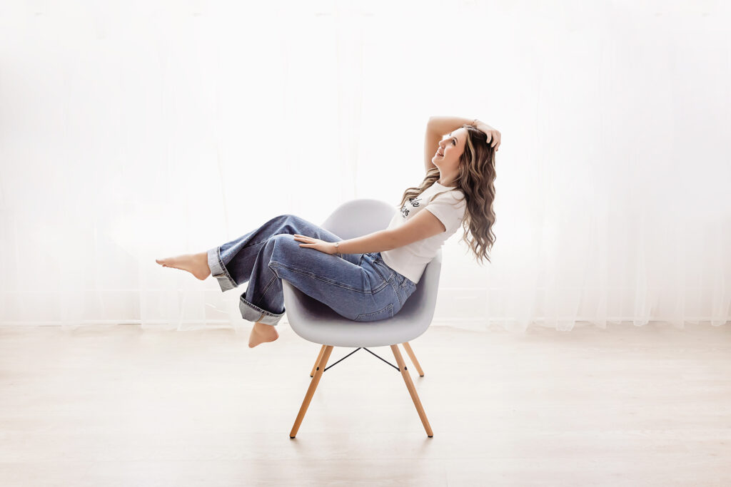 Addy laughing in a soft gray chair near the window, glowing with joy in natural light at Reflection Images by Tracy Rowell in Florence SC