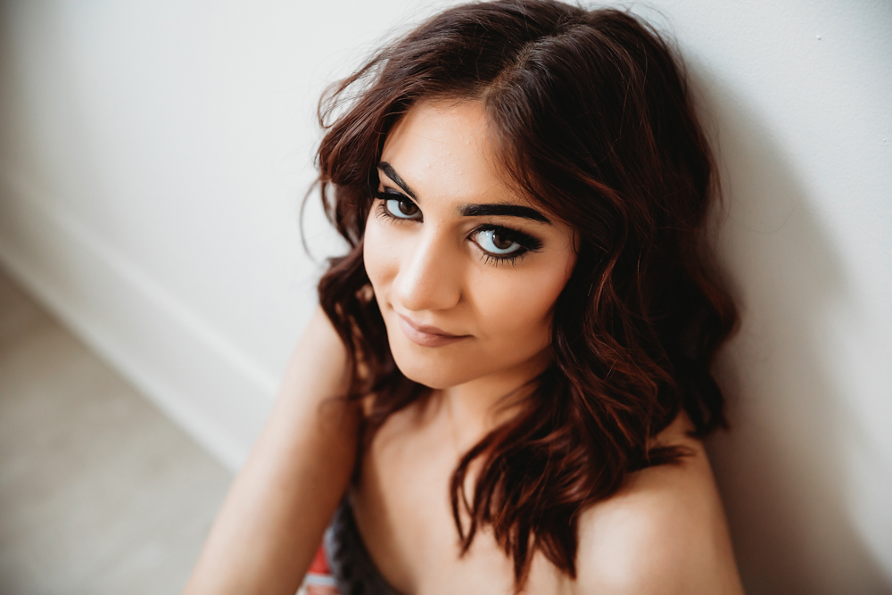 Patricia seated on floor leaning back against wall with expressive eyes and curled hair at Reflection Images by Tracy Rowell in Florence SC