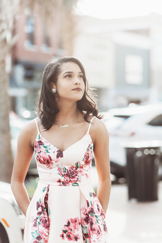 Connie gazing upward in a thoughtful pose on a downtown street, wearing her pink floral dress and pearl earrings at Reflection Images by Tracy Rowell in Florence SC