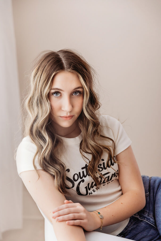 Close-up of Addy leaning forward in a chair, looking directly at the camera with confident eyes and curled hair at Reflection Images by Tracy Rowell in Florence SC