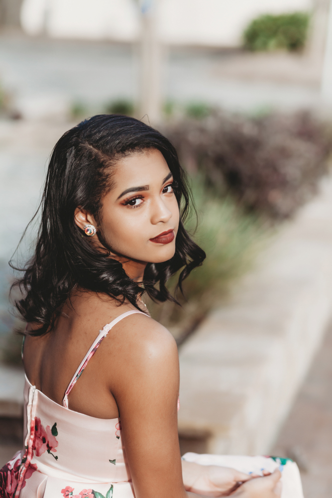Connie sitting on a stone ledge, glancing back over her shoulder with soft curls and warm makeup at Reflection Images by Tracy Rowell in Florence SC