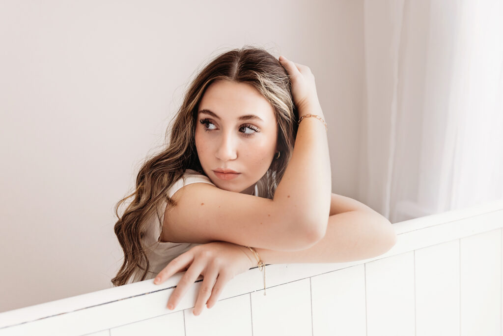 Addy resting her arms and looking to the side with loose waves and soft blush tones in natural studio light at Reflection Images by Tracy Rowell in Florence SC