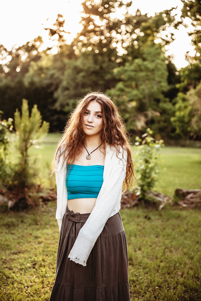 Eve standing in turquoise top and brown skirt, cream sweater, soft sunset glow in grassy field at Reflection Images by Tracy Rowell in Florence SC