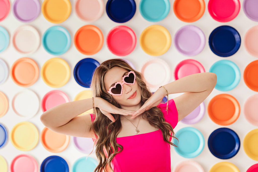 Teen girl wearing heart-shaped sunglasses striking a playful pose.