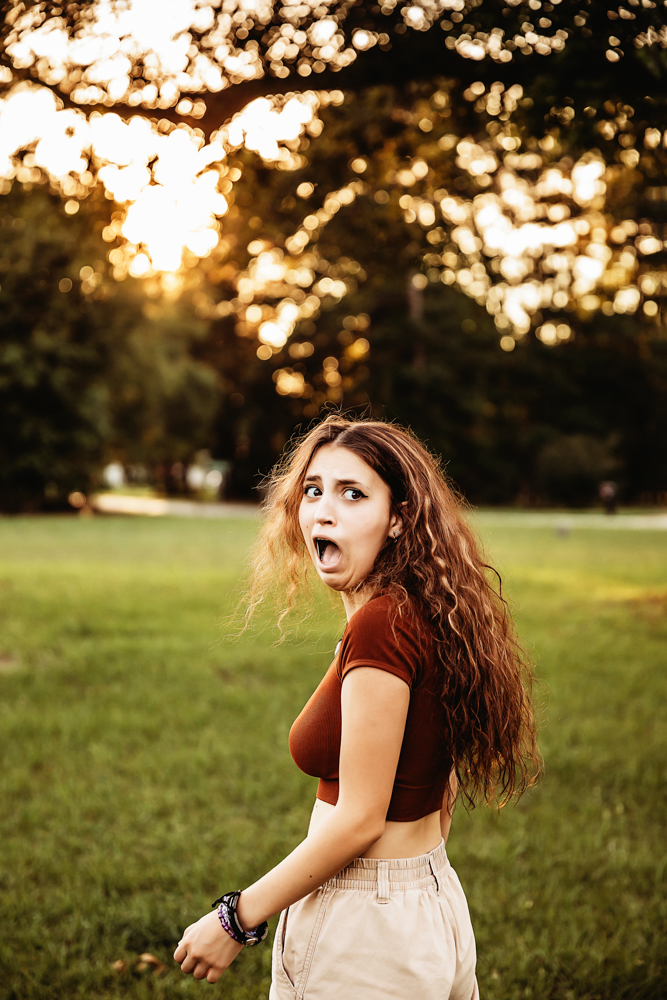 Eve making playful wide-eyed expression, rust top and khaki pants, candid moment in golden light at Reflection Images by Tracy Rowell in Florence SC