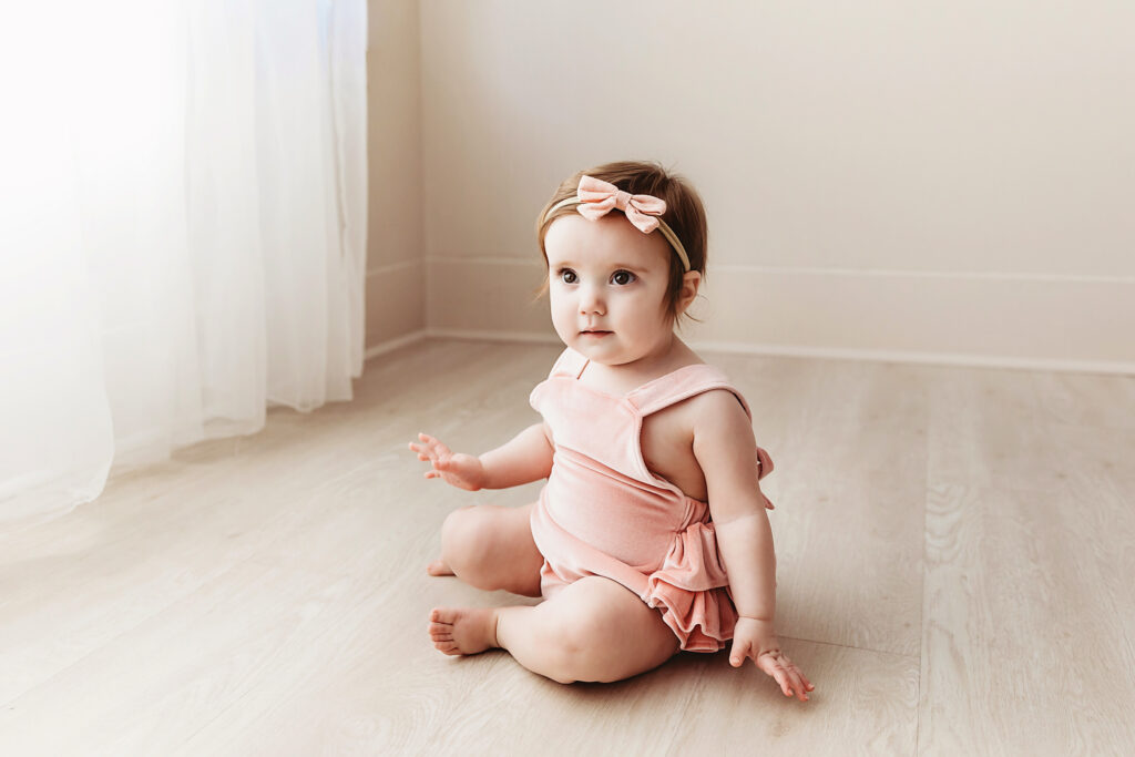 Sullivan sitting tall in her velvet romper with soft side light and a calm expression at Reflection Images by Tracy Rowell in Florence SC.