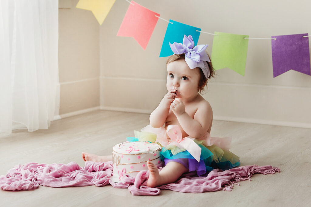 Close-up of Sullivans tiny feet pressing into birthday cake during a cake smash session in a rainbow tutu at Reflection Images by Tracy Rowell in Florence SC.