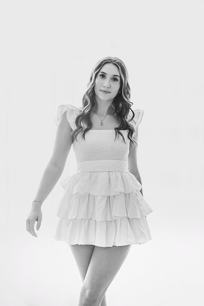 black and white of Teen girl standing against window wall in white dress with arm out at Reflection Images by Tracy Rowell in Florence SC