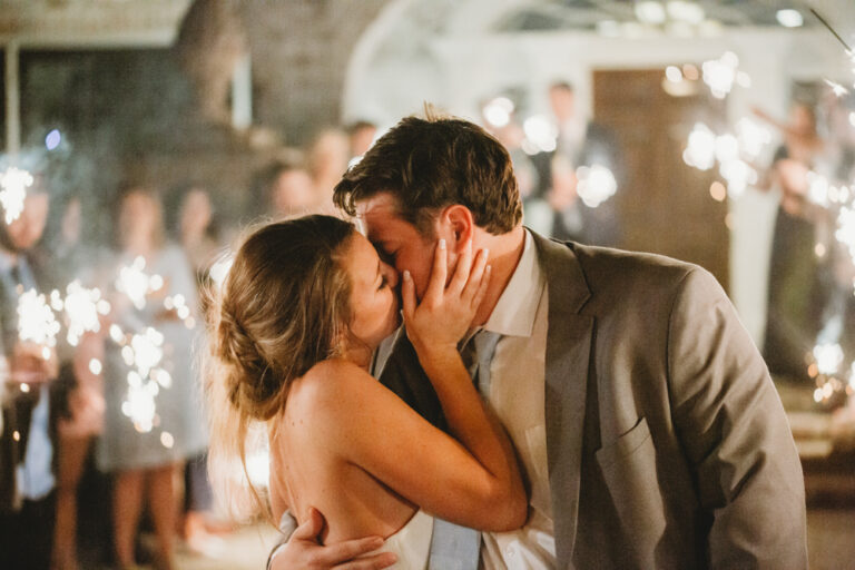 Couple kissing in sparkling exit with cheering guests at Reflection Images by Tracy Rowell in Florence SC
