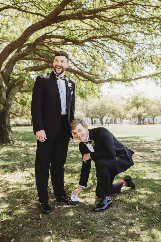 Wedding moment during groomsmen group shot, captured by reflection images by tracy rowell.