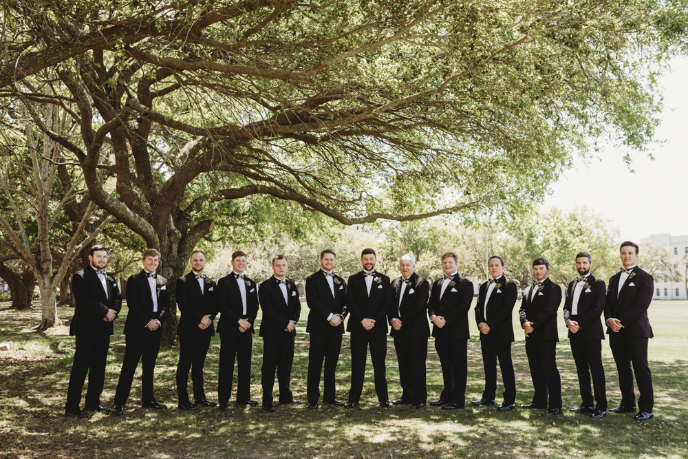 Wedding moment during groomsmen group shot, captured by reflection images by tracy rowell.