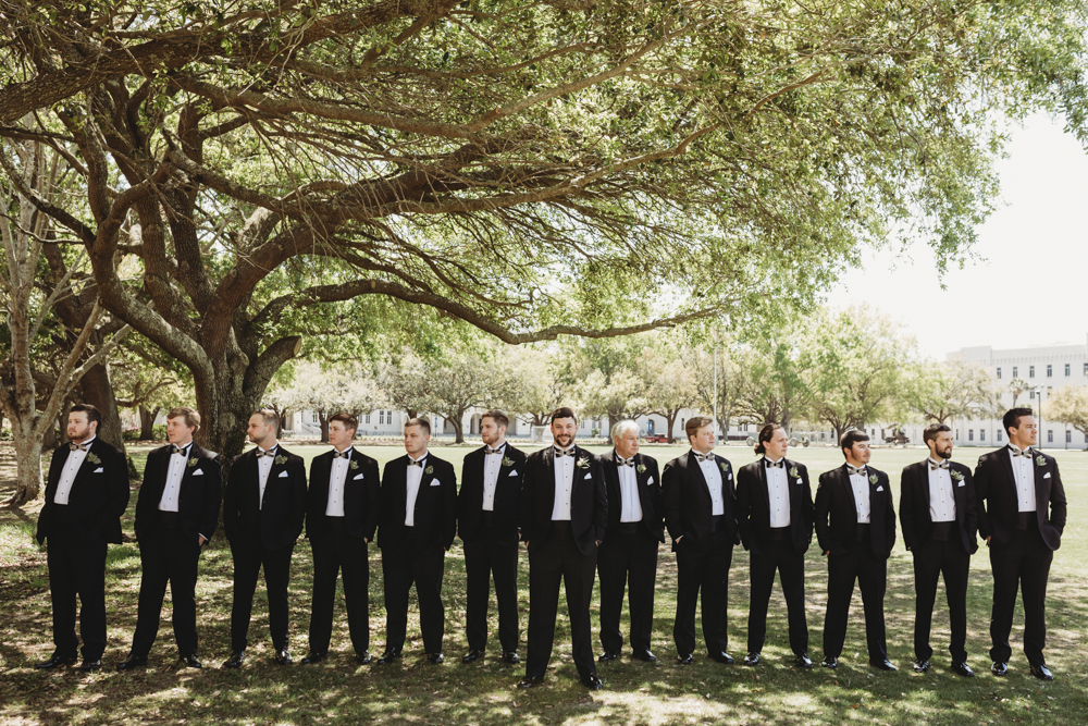 Wedding moment during groomsmen group shot, captured by reflection images by tracy rowell.
