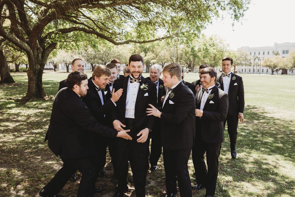 Wedding moment during groomsmen group shot, captured by reflection images by tracy rowell.