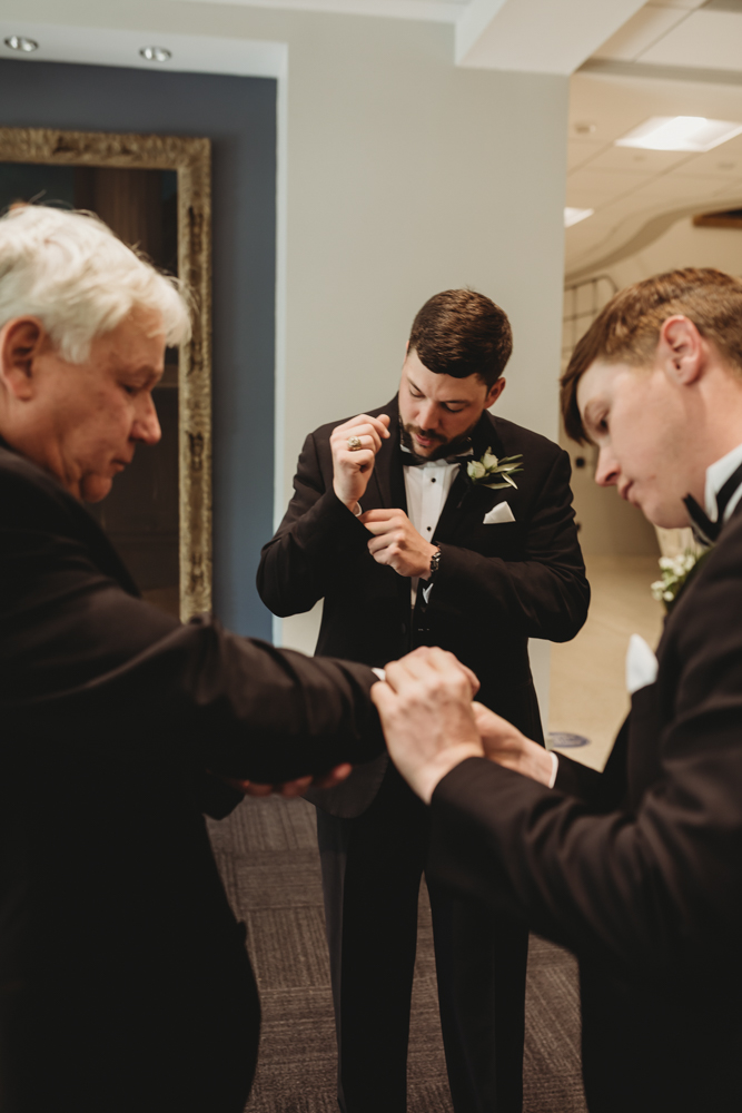 Wedding moment during groomsmen group shot, captured by reflection images by tracy rowell.