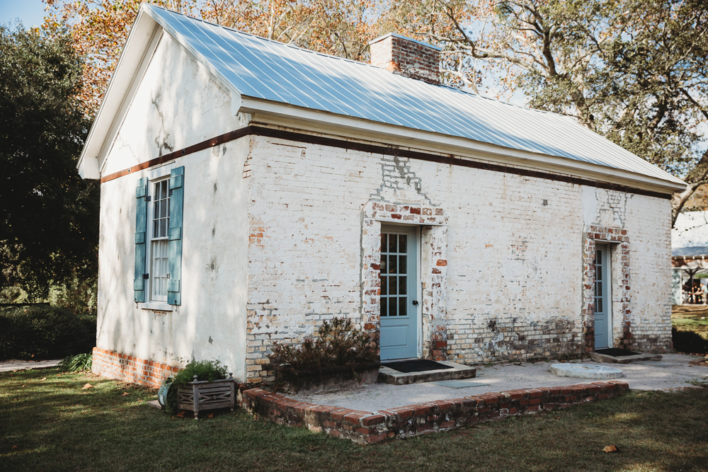 Historic white brick building with teal shutters and blue doors under autumn light at Wavering Place venue.