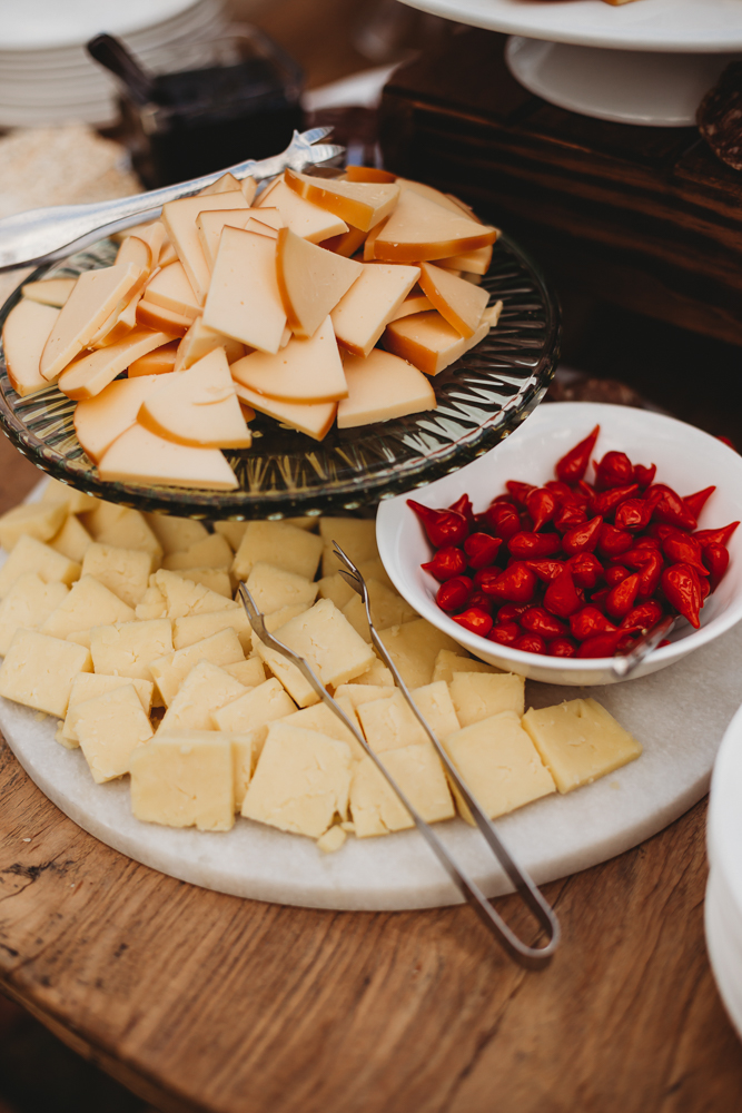 Assorted gourmet cheeses and bright red peppers arranged on glass and marble trays at the wedding cocktail hour at Wavering Place, captured by Reflection Images by Tracy Rowell in Florence SC.