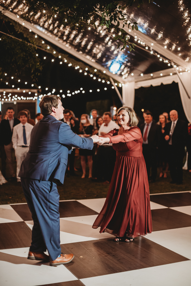 Groom dances with his mother on the black and white checkered floor beneath the tented reception at Wavering Place, by Reflection Images by Tracy Rowell in Florence SC.