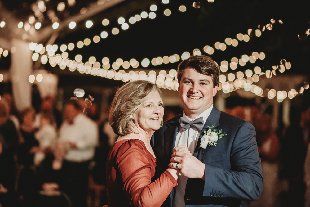 Groom and his mother smile during their dance under a canopy of twinkling lights at Wavering Place, photographed by Reflection Images by Tracy Rowell in Florence SC.