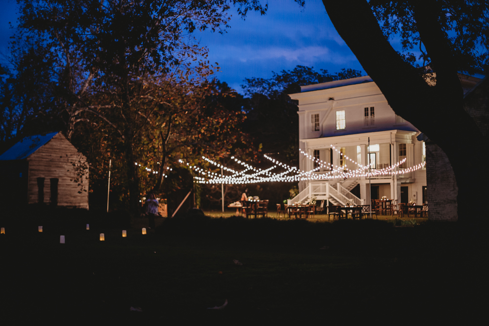Night view of Wavering Place lit up with string lights stretching across the lawn from the historic white house, photographed by Reflection Images by Tracy Rowell in Florence SC.