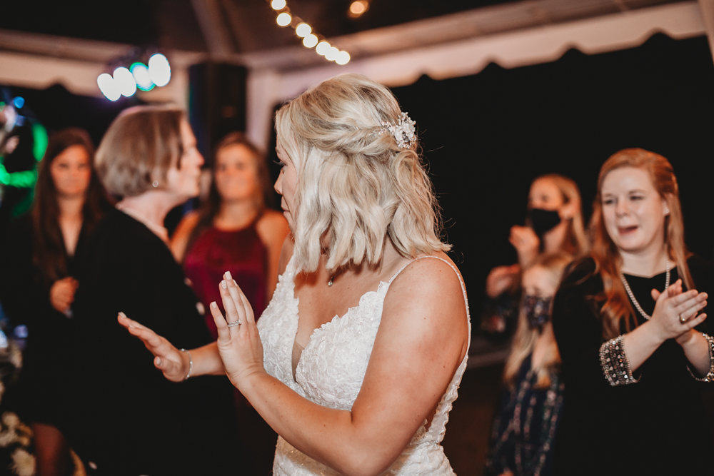 Bride Morgan dancing enthusiastically with guests under the glowing tent at Wavering Place during the wedding reception.