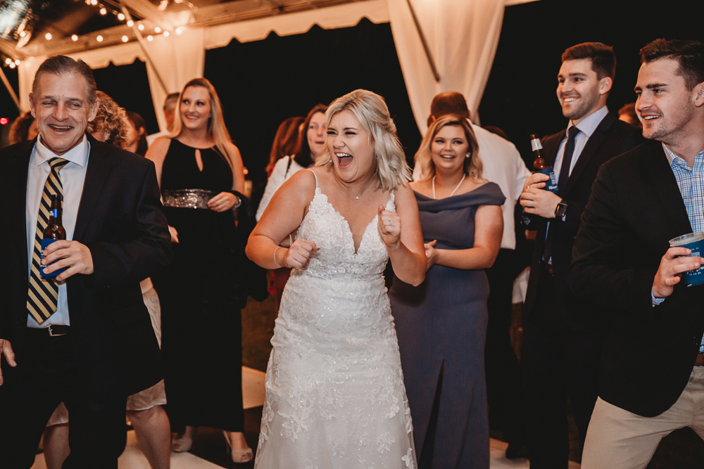 Bride Morgan laughing and dancing with guests during the joyful reception at Wavering Place, surrounded by friends and festive energy.
