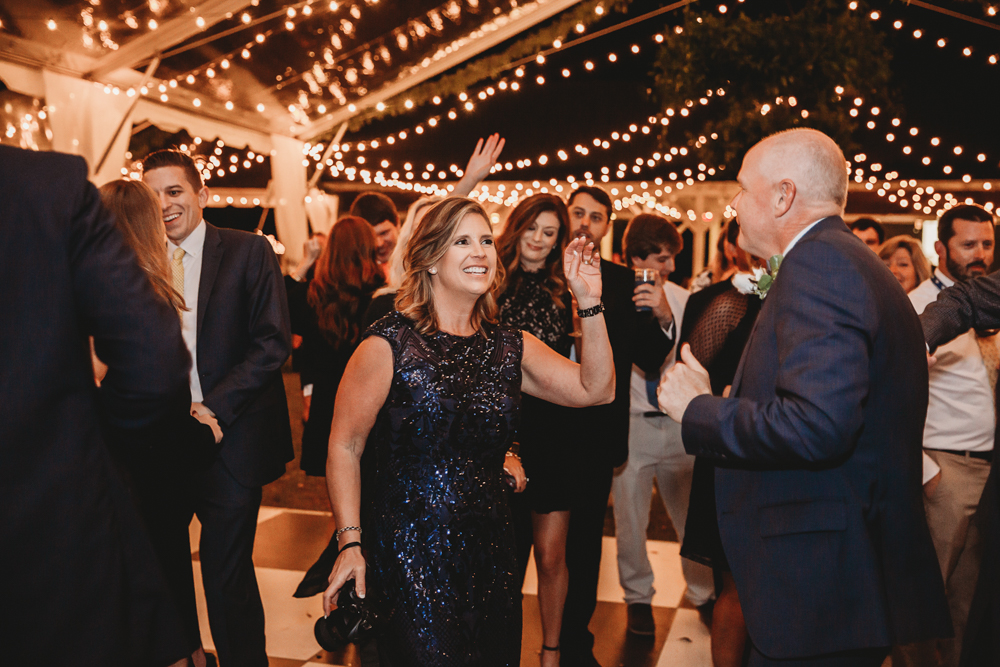 Parents of the couple dancing together under twinkling lights at Wavering Place while other guests enjoy the celebration.