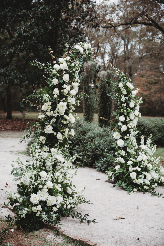 Floral arch bursting with white roses and lush greenery, set along the garden path at Wavering Place.