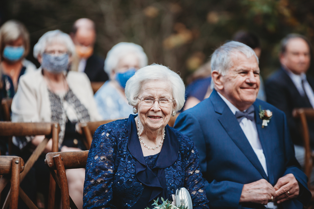 The bride’s grandparents smile from the front row of the ceremony, surrounded by other seated guests at Wavering Place.