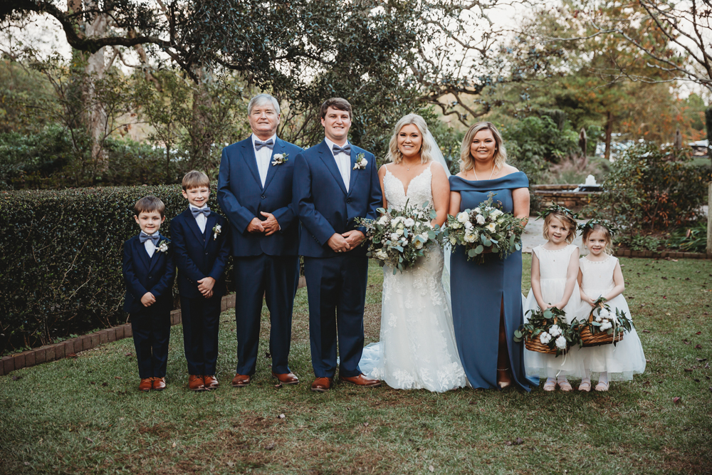 Group shot with ring bearers, flower girls in white dresses, and wedding party dressed in navy and dusty blue tones at Wavering Place in Eastover, SC